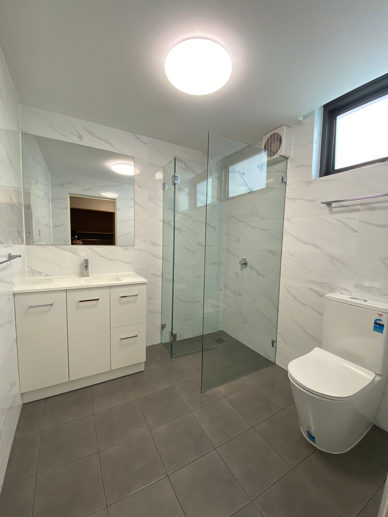 Marble-look tiled bathroom with glass shower